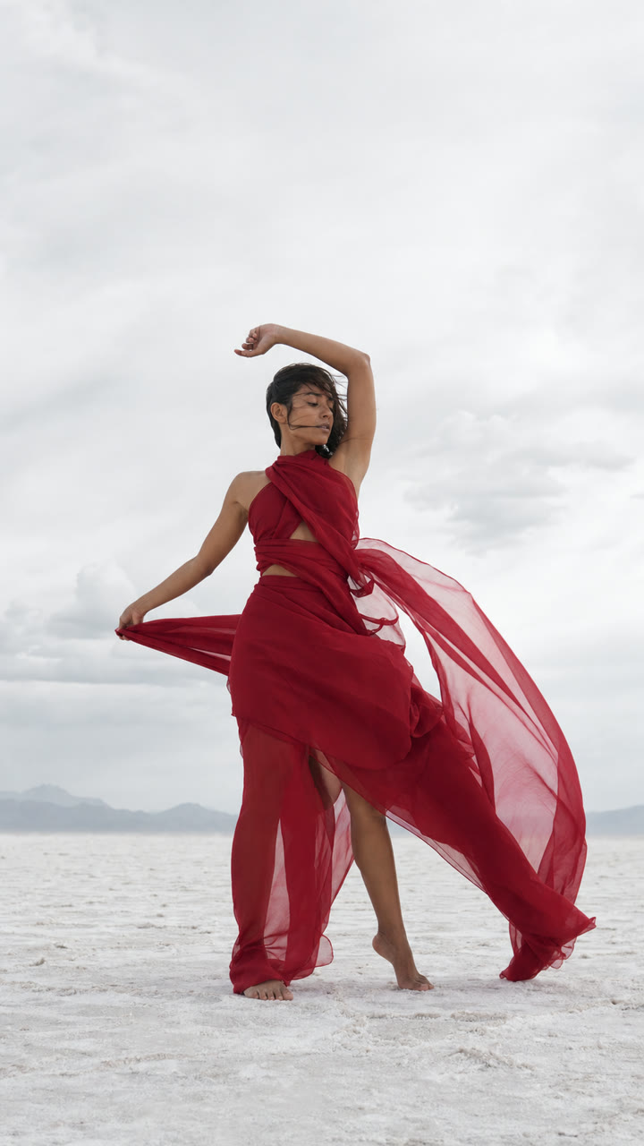 Fashion dancer in flowing red fabric on a white salt flat
